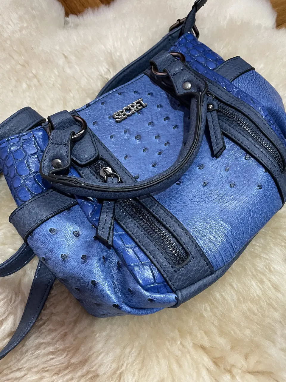 Cartera azul Secret, con detalles de textura y cierres. Ideal para llevar tus esenciales con estilo.