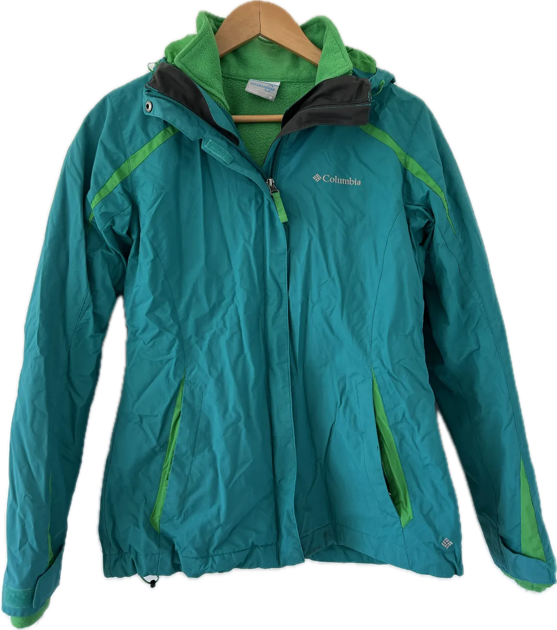 Campera Columbia Interchange para mujer, color turquesa con detalles en verde. Incluye un forro polar interior desmontable. Ideal para actividades al aire libre y climas fríos.