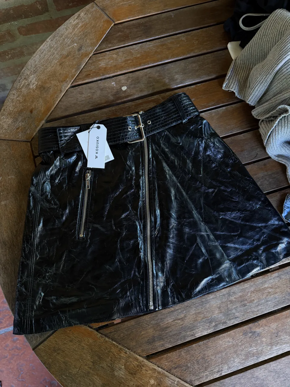 Pollera negra corta con cinto y dos cierres frontales.