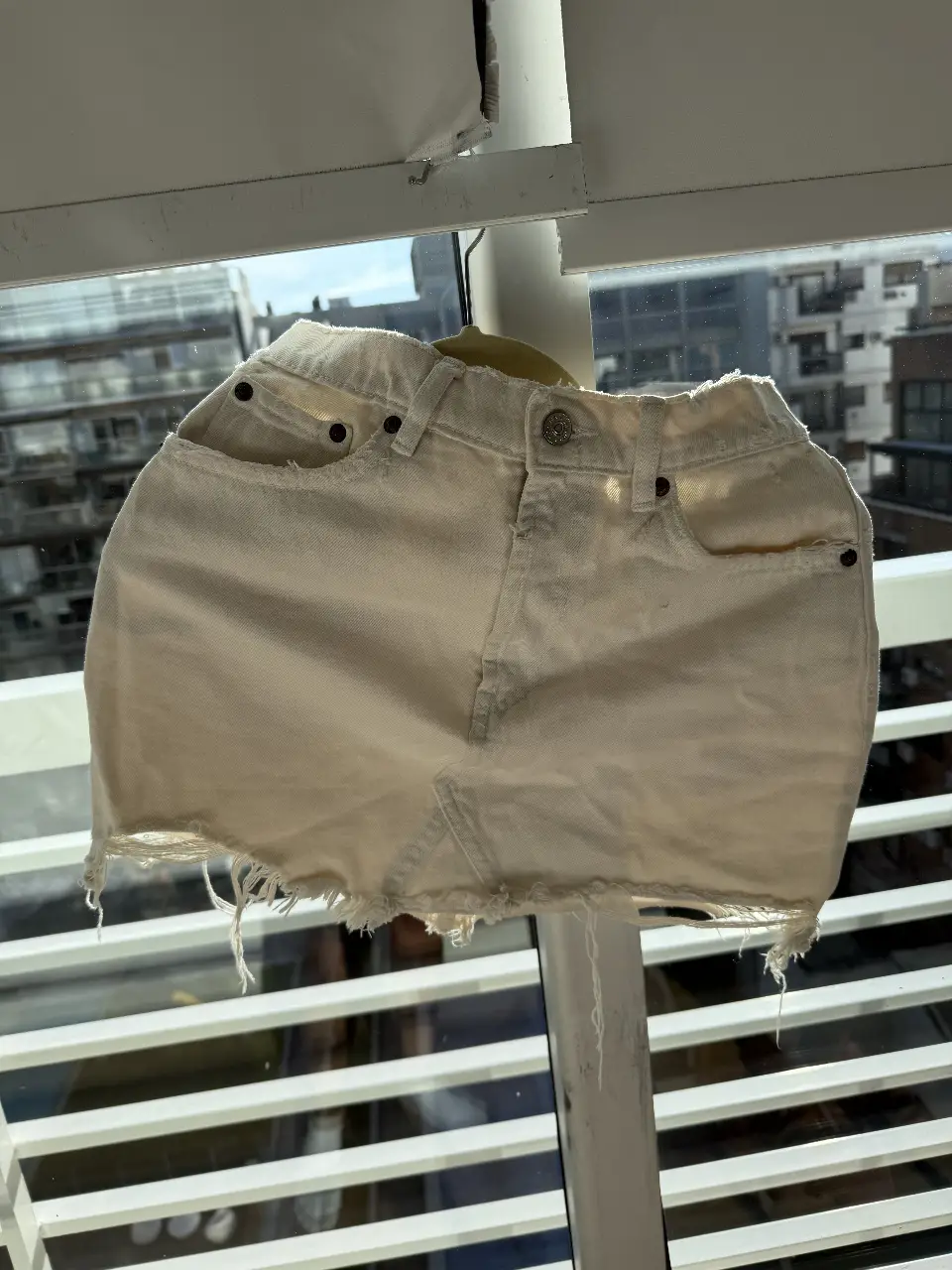 Minifalda de jean color crudo, con detalles de roturas en el borde inferior. Ideal para un look casual y moderno.