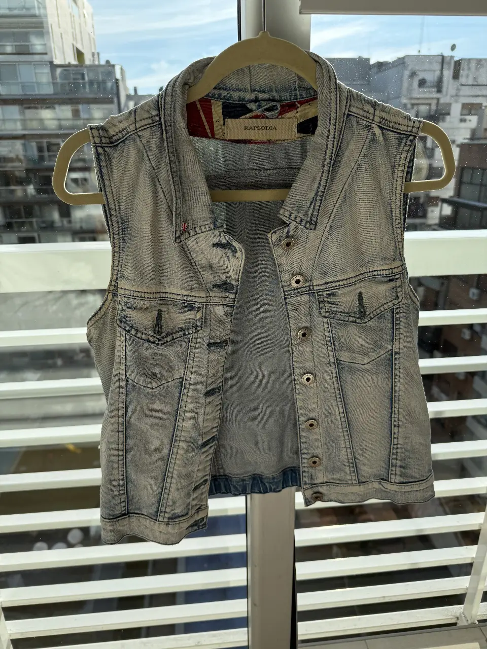 Chaleco de jean celeste claro de la marca Rapsodia, con detalles de botones y bolsillos. Ideal para un look casual y canchero.