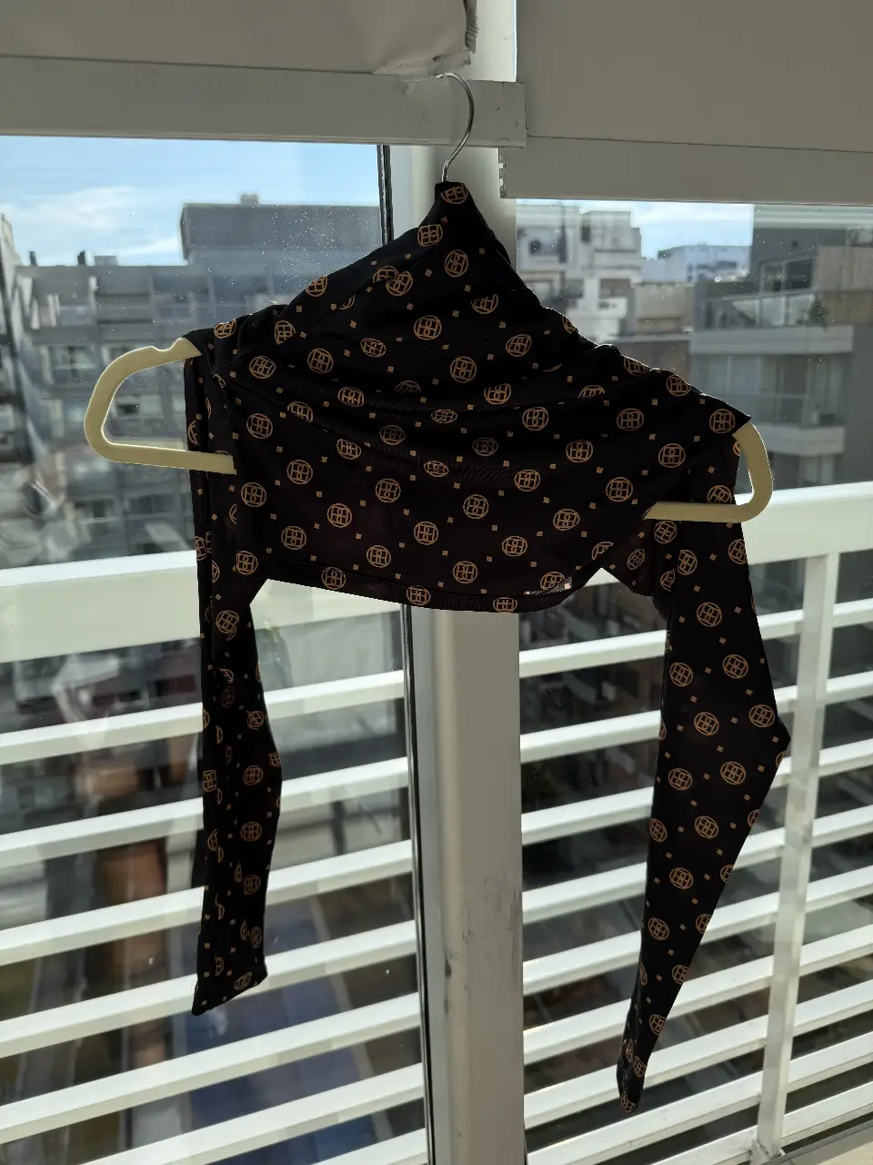 Top de cuello alto con estampado geométrico en tonos dorados sobre fondo negro. Ideal para un look elegante y moderno.