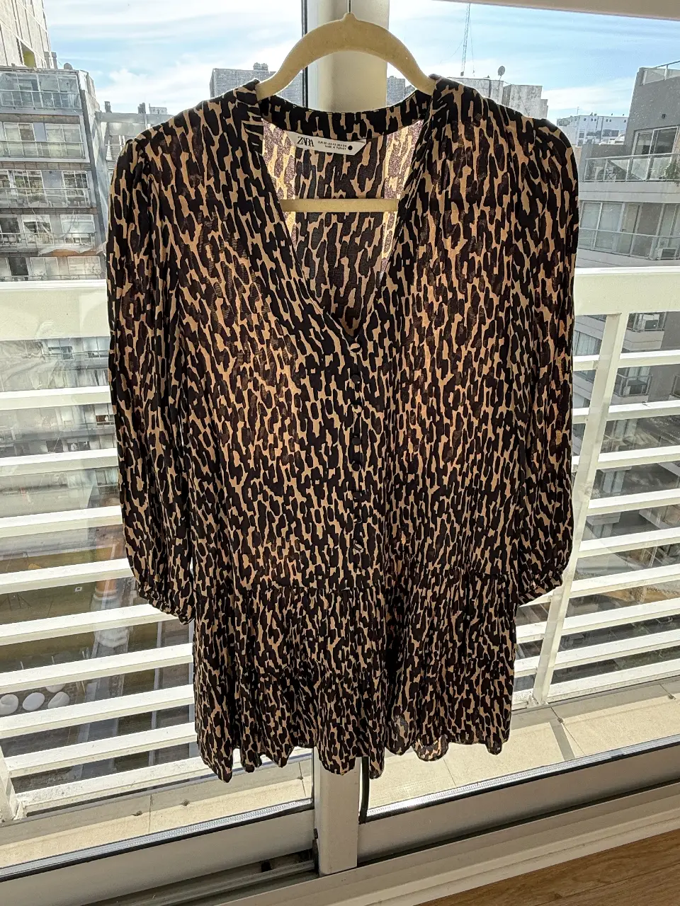 Vestido mini de mujer con estampado animal print. Cuello en V, mangas largas y volados en la falda. Ideal para un look casual y moderno.