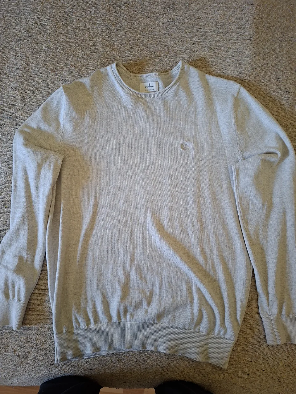 Sweater de hombre de color gris claro, de cuello redondo y manga larga. Ideal para un look casual y cómodo.