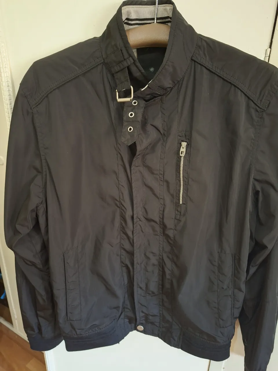 Campera negra de hombre, estilo bomber, con cierre y cuello alto. Ideal para un look casual y moderno.
