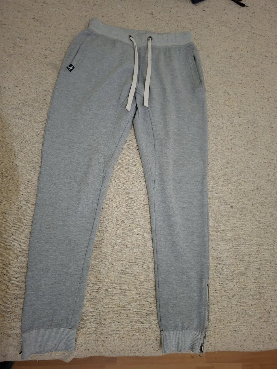 Pantalón de hombre de jogging gris, con logo bordado y cierre en los tobillos. Marca Brooksfield, talle M.