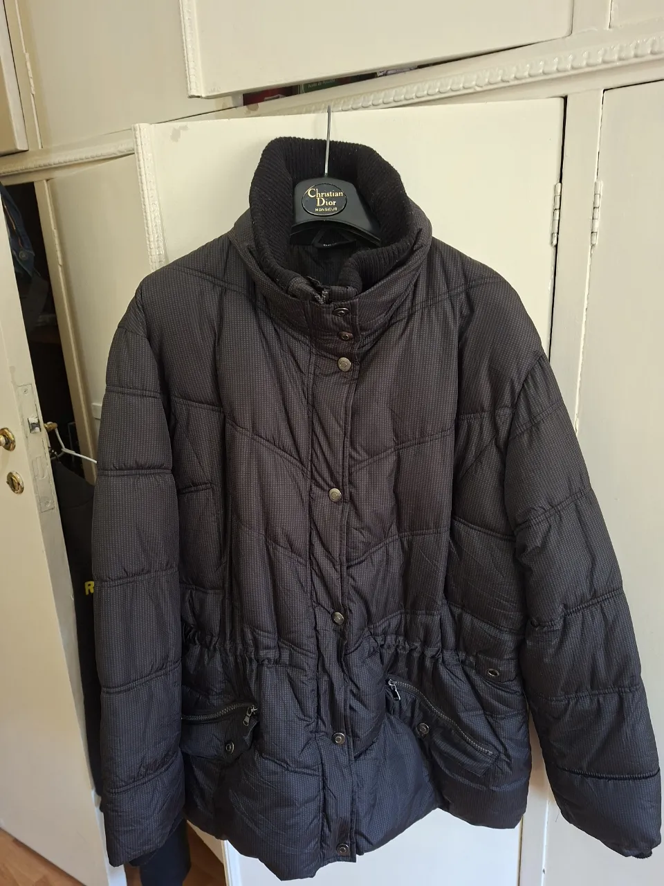 Campera de pluma negra, con cuello alto y ajuste en la cintura. Ideal para el invierno.