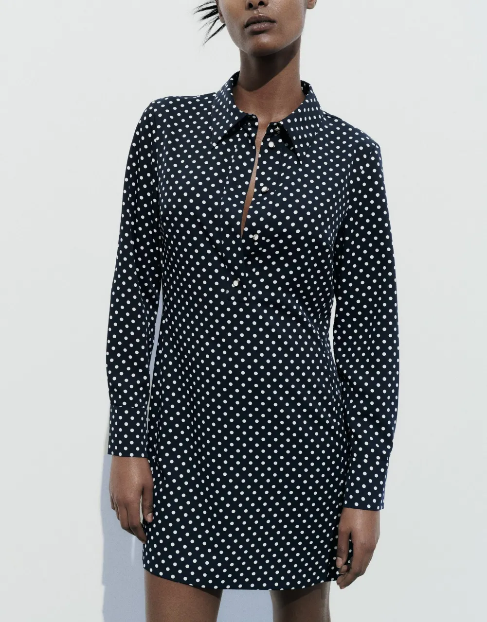 Vestido midi de mujer con estampado de lunares blancos sobre fondo azul marino. Diseño de camisa con cuello, botones delanteros y mangas largas.