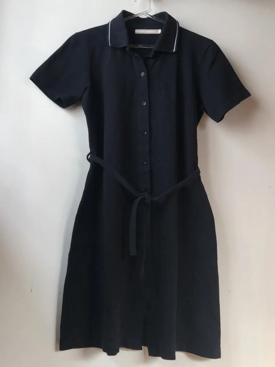 Vestido midi negro marca Southland, con cinturón, de corte clásico y elegante. Ideal para un look versátil, apto para el trabajo o una salida casual. Confeccionado en tela de calidad, este vestido ofrece comodidad y estilo.