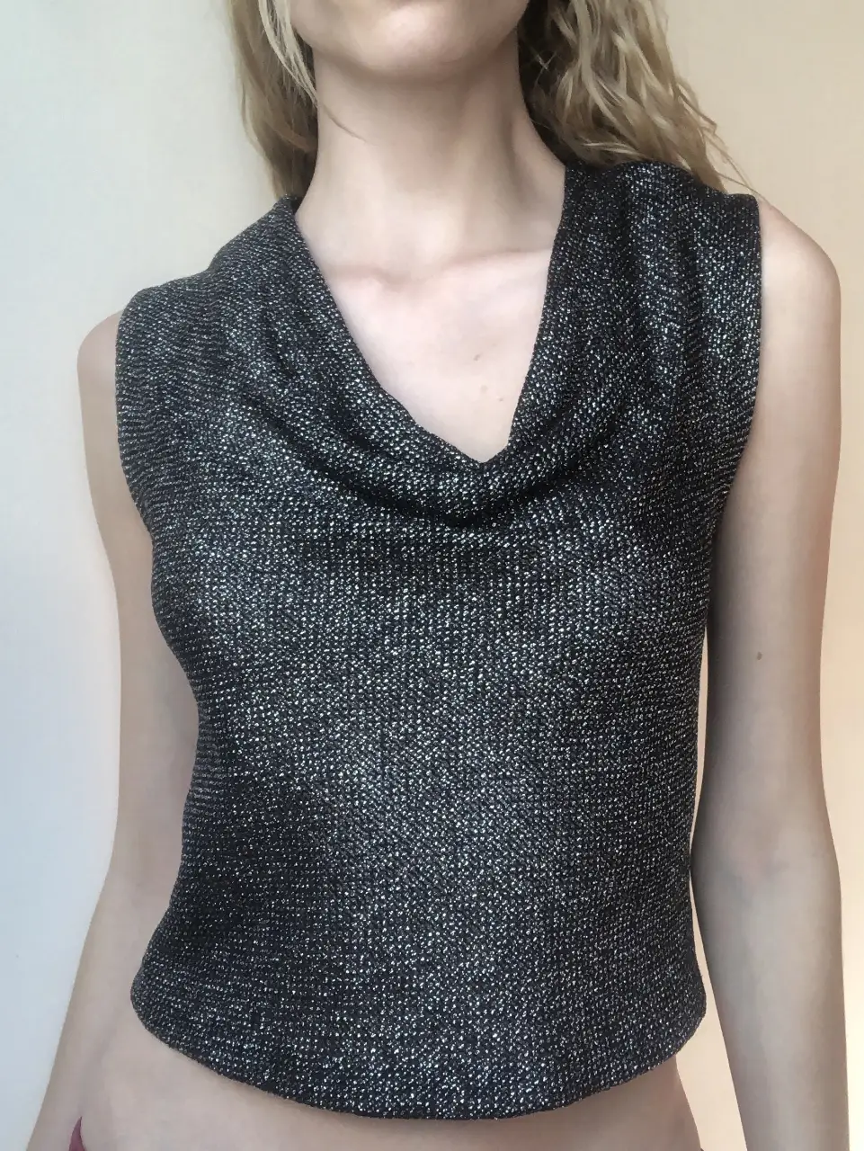 Top sin mangas de tejido brillante con cuello abuchonado. Ideal para una salida nocturna o evento especial. Estilo elegante y moderno.