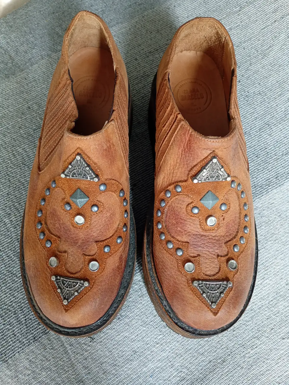 Botines de cuero marrón con plataforma y detalles metálicos. Estilo artesanal y retro, ideales para un look casual y con onda.
