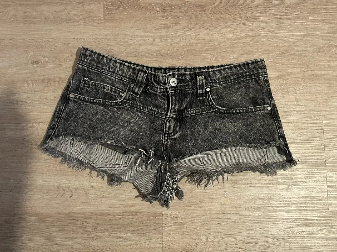 Short de jean negro con detalles desflecados, tiro medio/bajo y talle 24. Ideal para un look casual y moderno. de lovely denim 