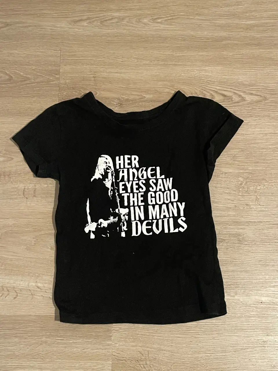 Remera negra de algodón con estampado "Her angel eyes saw the good in many devils". Talle S, ideal para un look rocker o casual.