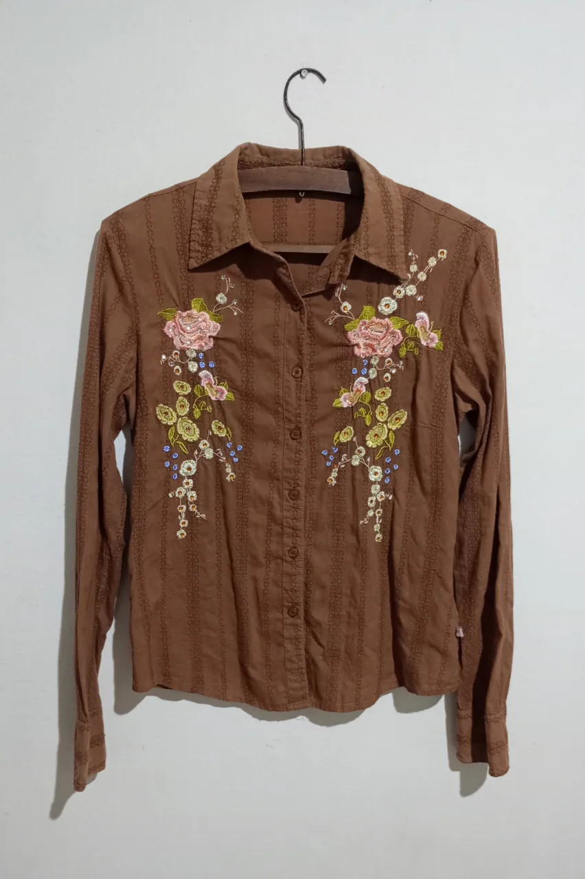 Camisa marca Kosiuko, talle S, con detalles de bordado. Medidas aproximadas tomadas en plano: hombros 39 cm, sisa 45 cm, largo 58 cm.