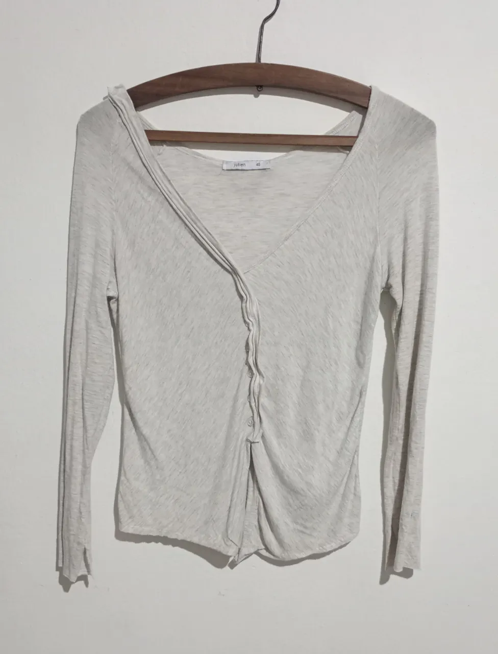 Saquito marca Julien de manga larga color gris claro con escote en V cruzado y  botones. En la espalda tiene una cadena metálica con el nombre 'Julien' grabado.  Talle 40. Medidas aprox. en plano: hombros 31 cm, sisa 39cm, largo 50