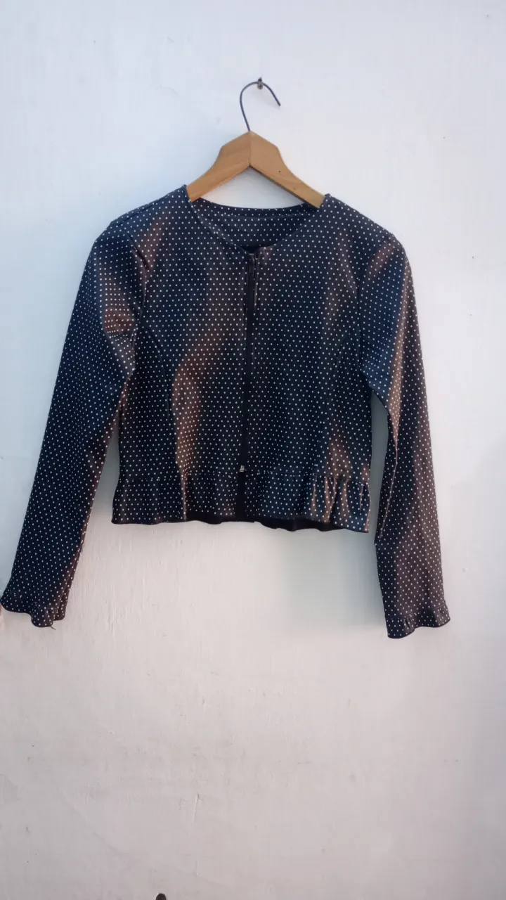 Campera fina, para media estación. Talle S. Medidas aprox. en plano: hombros 36 cm, sisa 38 cm, largo 42 cm. Posee cierre al frente y volado en el ruedo y en los puños.