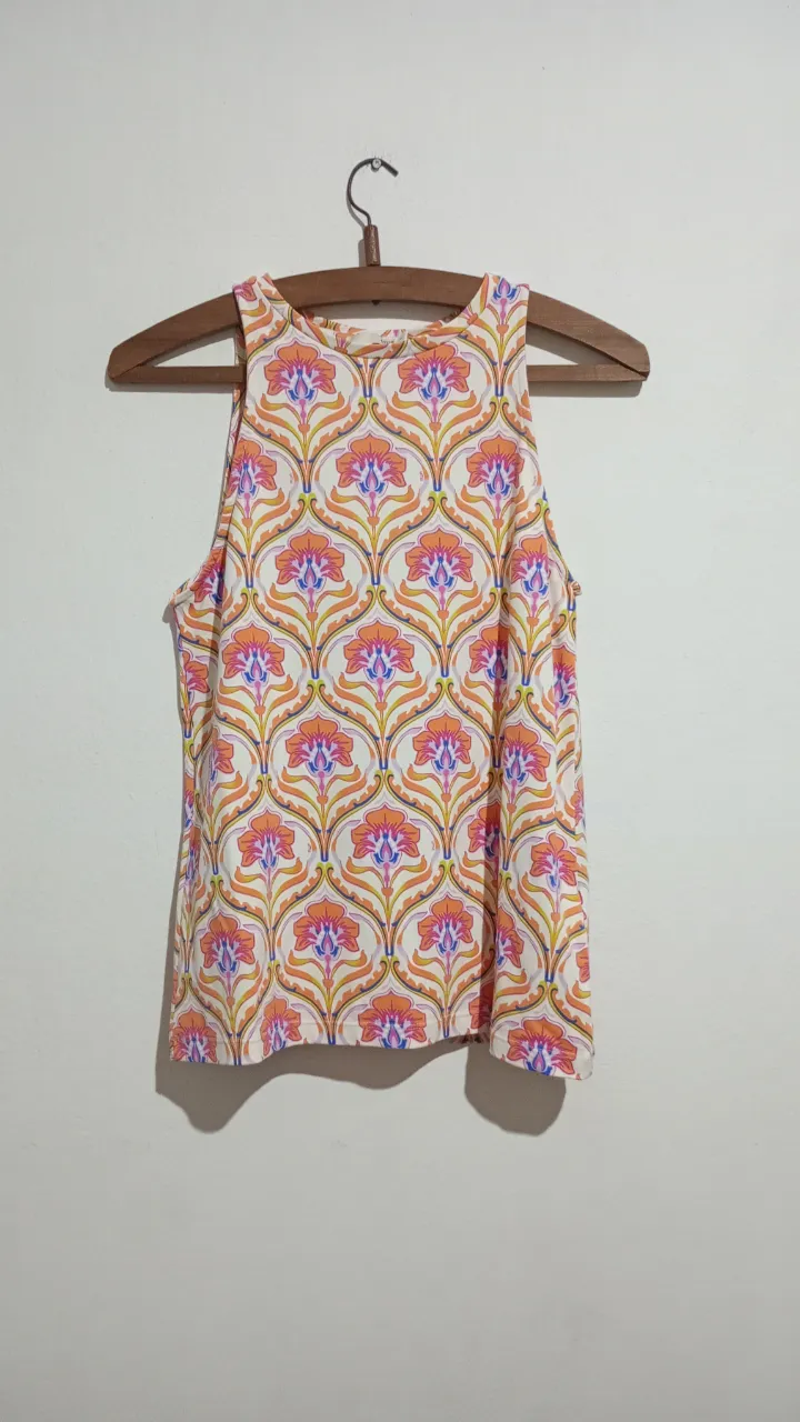 Musculosa blanca con estampa floral geométrica en tonos naranja, rosa, azul y amarillo. Cuello redondo. Marca Uma. Talle 1, va como para un M igual, y es elastizada. Medidas aprox. en plano: Sisa 40 cm, largo 58 cm.
