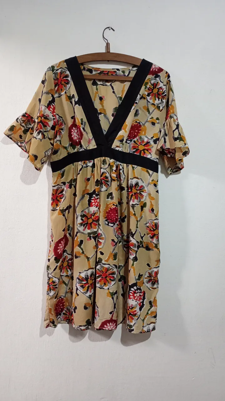 Vestido con estampado floral en tonos amarillos, rojos y verdes. Posee escote en V con vivos negros y cintura elastizada. Las mangas son cortas y con volados. Marca Rapsodia, talle L 46/48. Tiene lazo para ajustar la cintura en la parte de la espalda, cierre al costado. Medidas aprox en plano: hombro 38 cm, sisa 48 cm, bajo busto/cintura alta 40 cm, largo 90 cm.