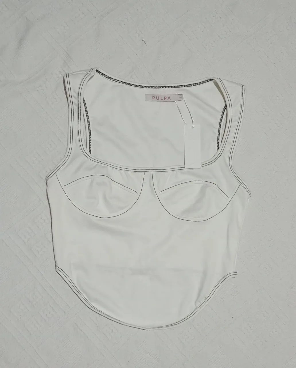 Top blanco con pespuntes negros. Escote cuadrado y busto con pinzas.Talle 2. Nuevo con etiqueta, forma tipo corset, pero sin estructura. Elastizado. Medidas aprox. en plano: Sisa 38 cm, largo delantero 49 cm, largo trasero 33 cm.