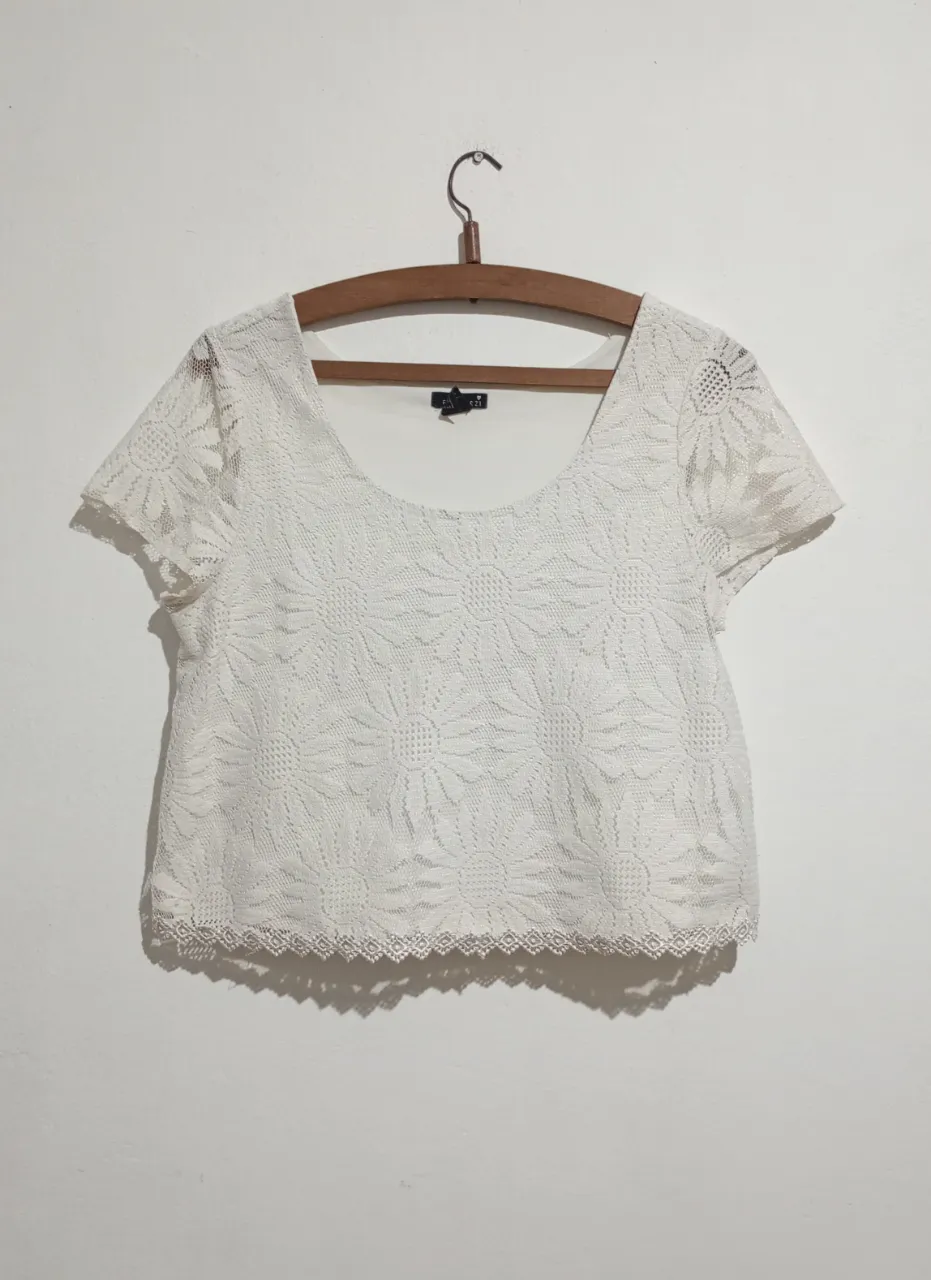 Top blanco de encaje con flores y borde festoneado. Crop top marca Forever 21. Tela calada forrada. Talle M. Medidas aproximadas tomadas en plano: hombros 37 cm, sisa 42 cm, largo 46 cm.