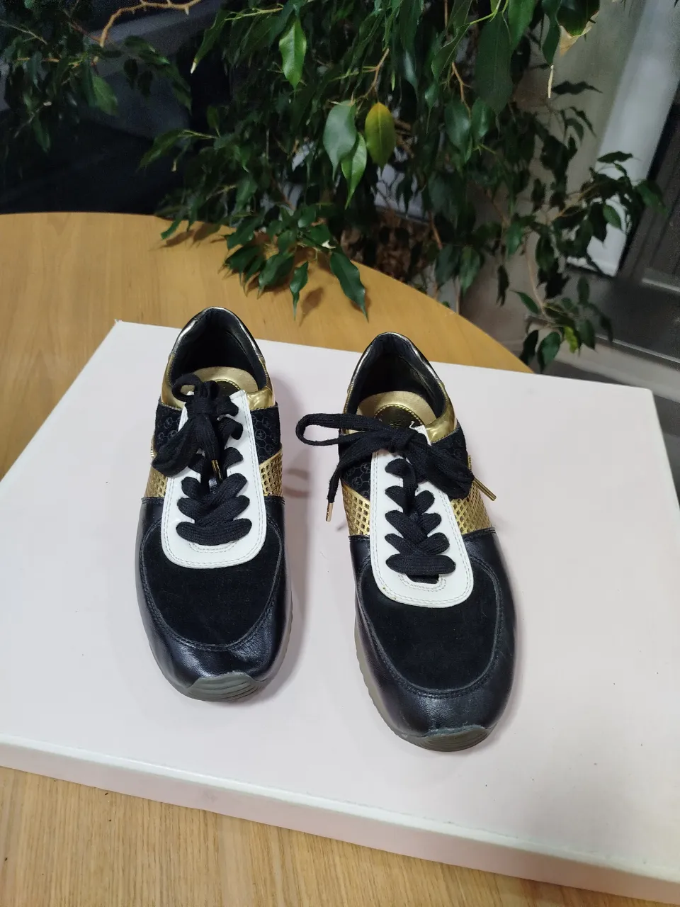 Zapatillas Michael Kors de mujer en color negro con detalles dorados y blancos. Diseño moderno y elegante, ideales para un look casual y cómodo.