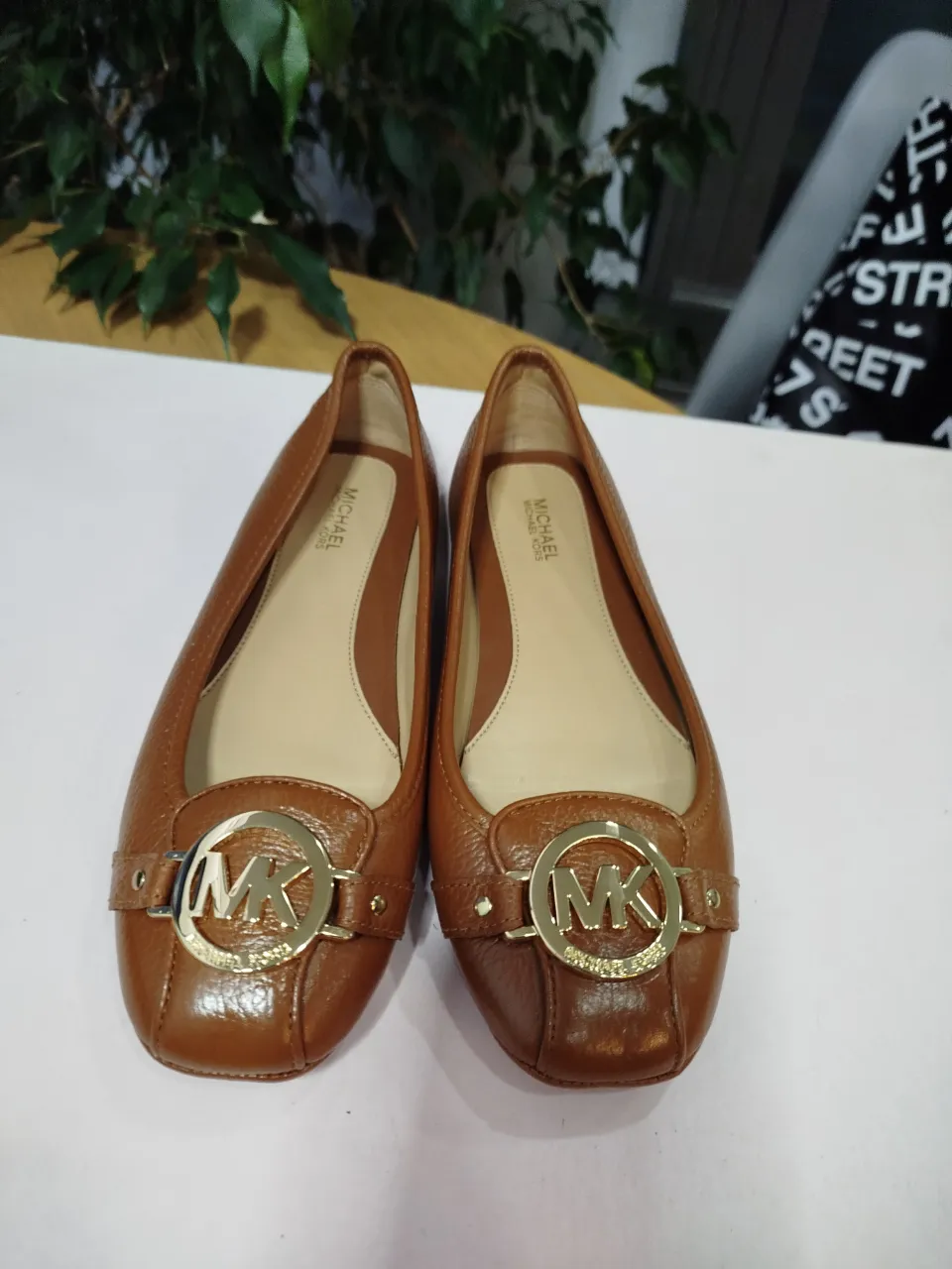 Ballerinas Michael Kors de cuero marrón con detalle de logo dorado. Ideales para un look elegante y cómodo.