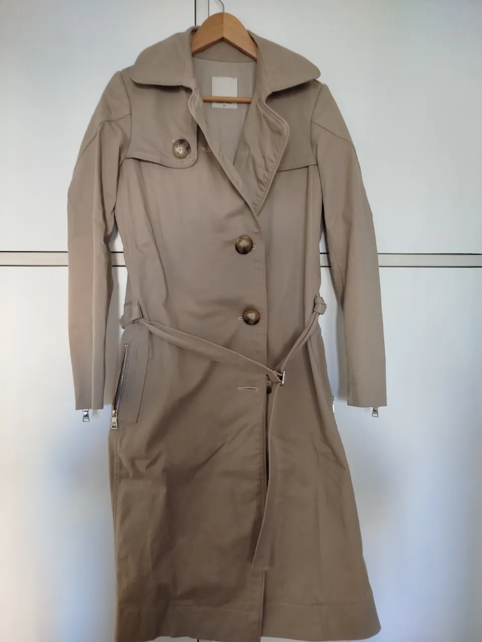 Trench coat beige con bordado "Romantic" en la espalda. Posee cinturón para ajustar la cintura, botones y cierre en las mangas. Ideal para un look elegante y a la moda. Con pequeño detalle en el cuello se ve en las fotos