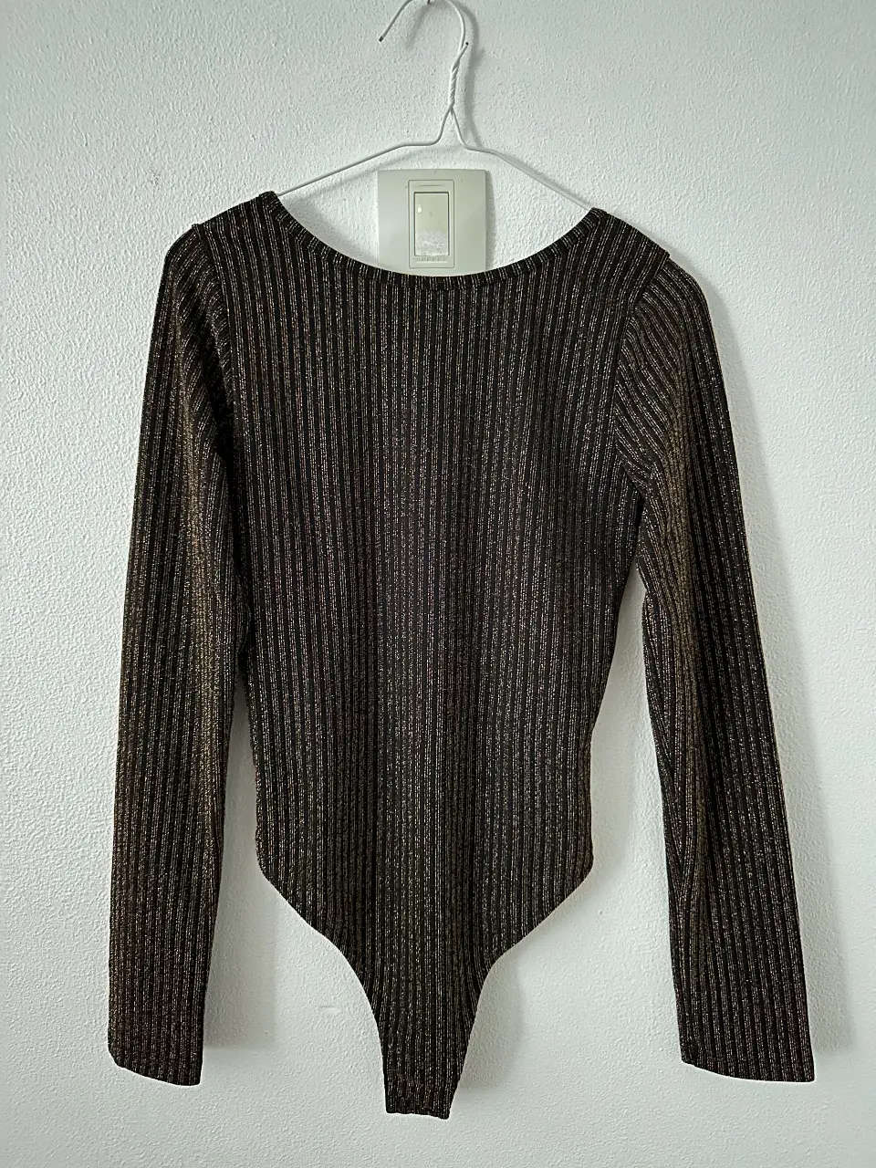 Body de manga larga con diseño de rayas doradas sobre fondo negro. Ideal para un look de fiesta o salida. Un solo uso. 