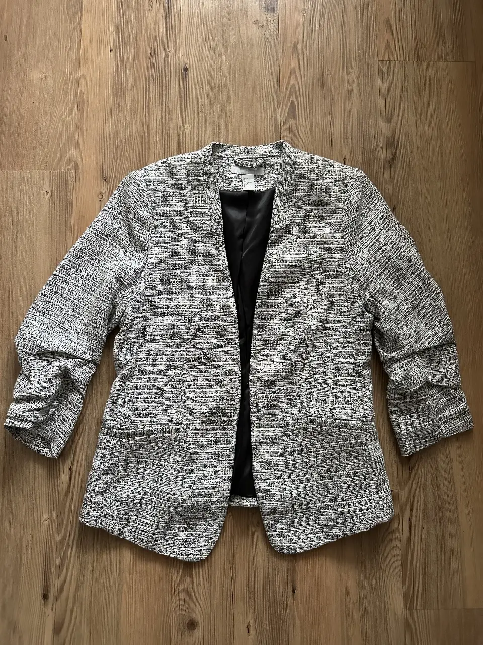 Blazer de mujer, con diseño de tweed en tonos grises y negros. Corte clásico con solapas y mangas 3/4. Ideal para un look elegante y sofisticado.