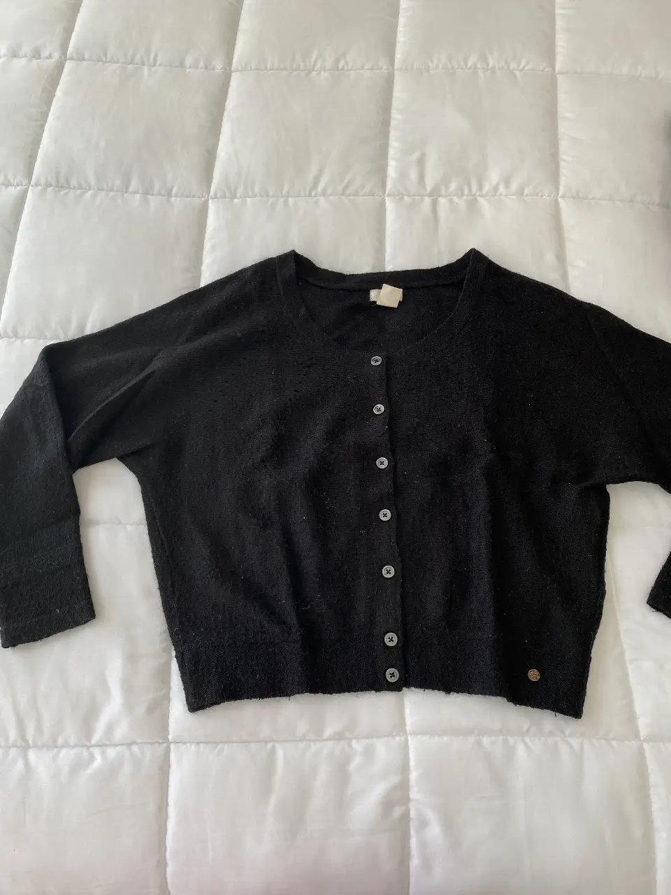 Cardigan negro de punto, con botones y cuello redondo. Ideal para un look casual y abrigado.