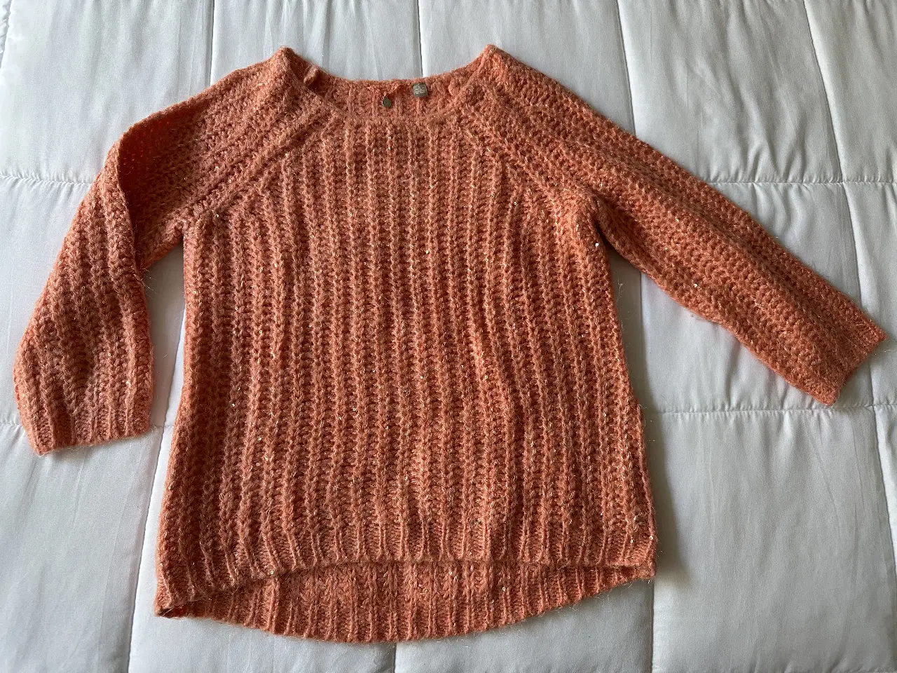 Sweater tejido de color naranja con detalles de lentejuelas. Cuello redondo y mangas 3/4. Ideal para un look casual y abrigado.