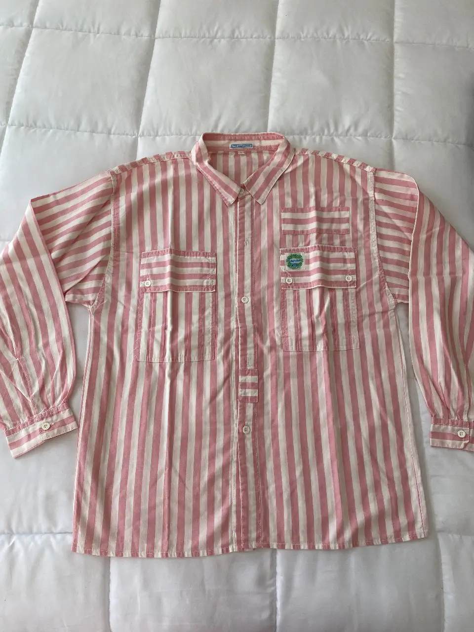 Camisa de hombre a rayas rosas y blancas, con dos bolsillos delanteros y un parche con logo. Oversize. Ideal para un look casual y fresco.