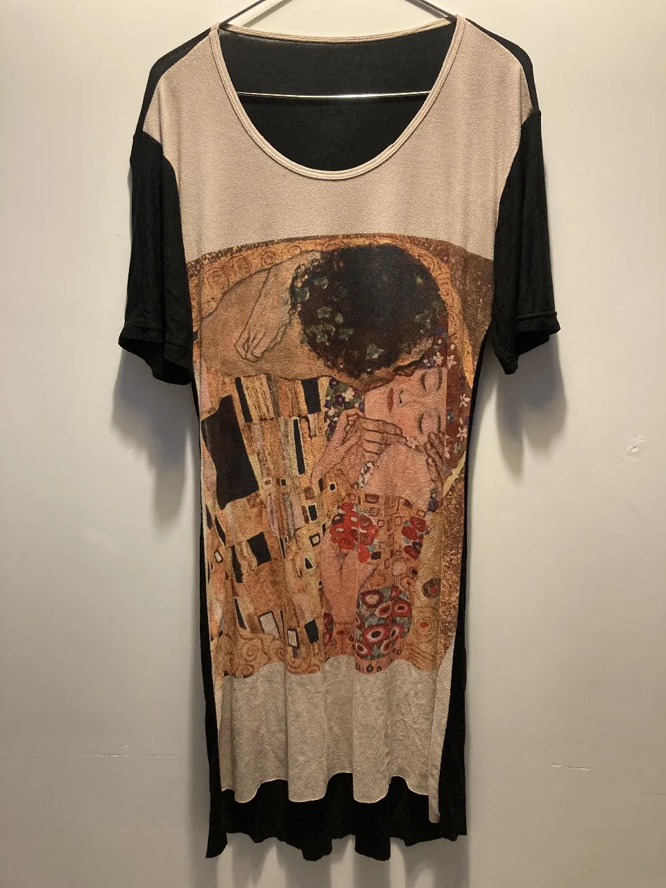 Vestido con estampado del famoso cuadro "El Beso" de Gustav Klimt. Diseño con mangas cortas negras. Entalla la figura pero la tela tiene buena caída  por lo que no ajusta.
Largo total (desde el hombro al final): 89cm en el frente y 96 atrás.