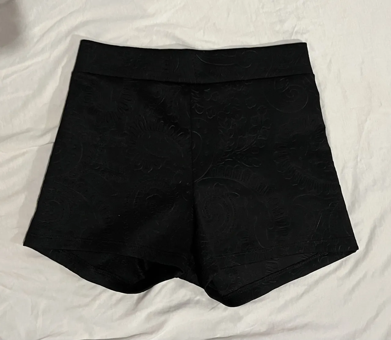 Shorts negros con un delicado diseño en bajo relieve. Ideales para un look elegante y sofisticado, perfectos para una salida o una fiesta.