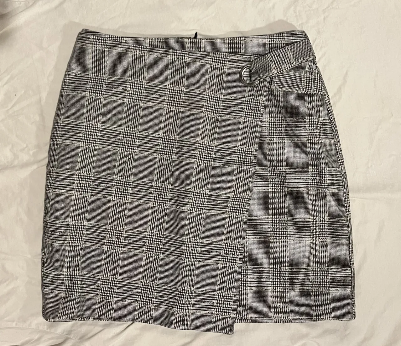 Pollera corta a cuadros escoceses, con detalle de hebilla metálica y corte asimétrico. Ideal para un look moderno.