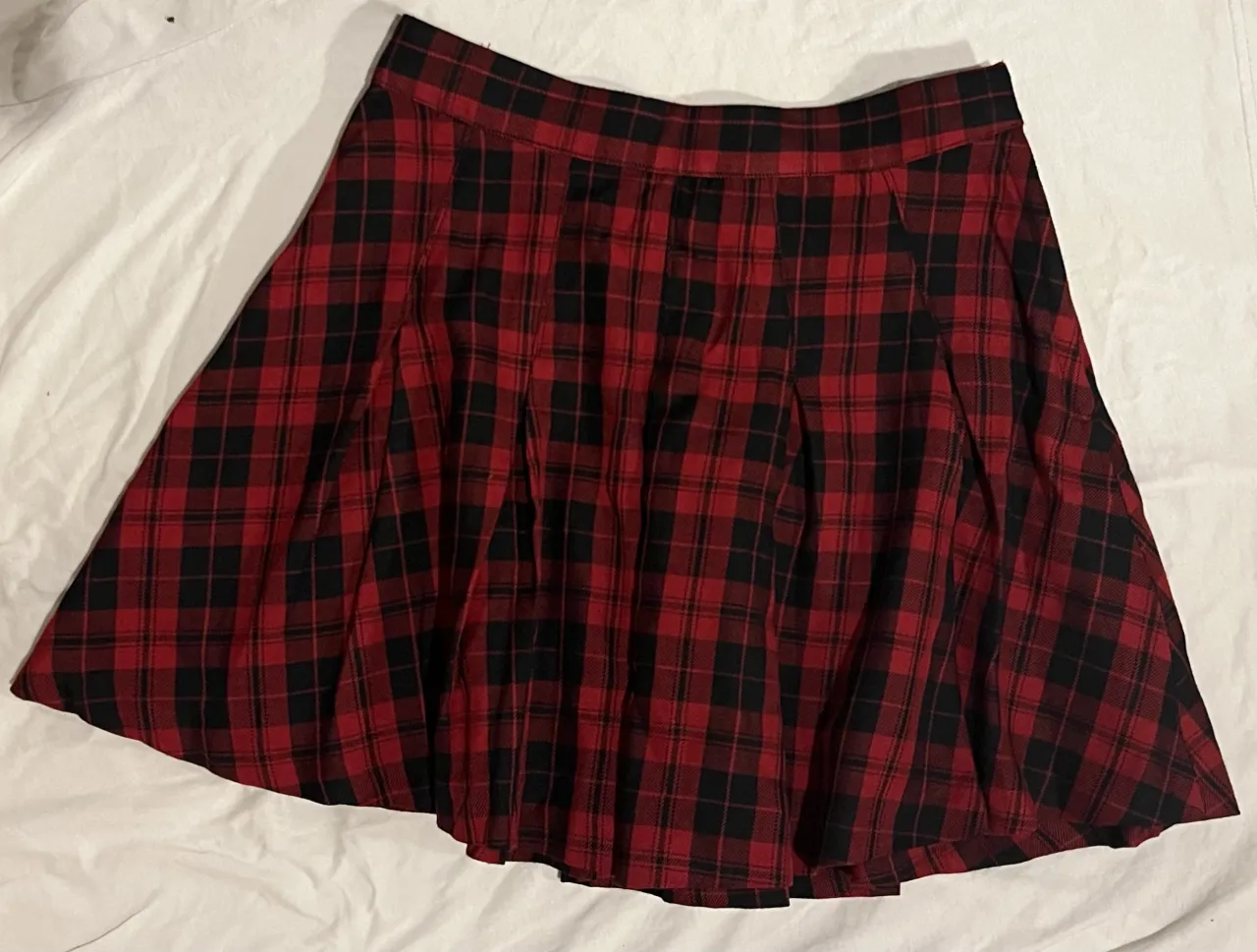 Pollera corta a cuadros escoceses, ideal para un look rocker o Y2K. Combina rojo y negro, perfecta para usar en cualquier estación y para salidas informales o fiestas.