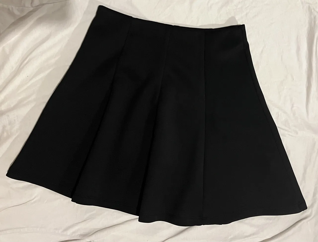 Pollera negra corta, ideal para cualquier ocasión. Su diseño versátil la hace perfecta para combinar con diferentes tops y calzado, creando looks tanto casuales como más arreglados.