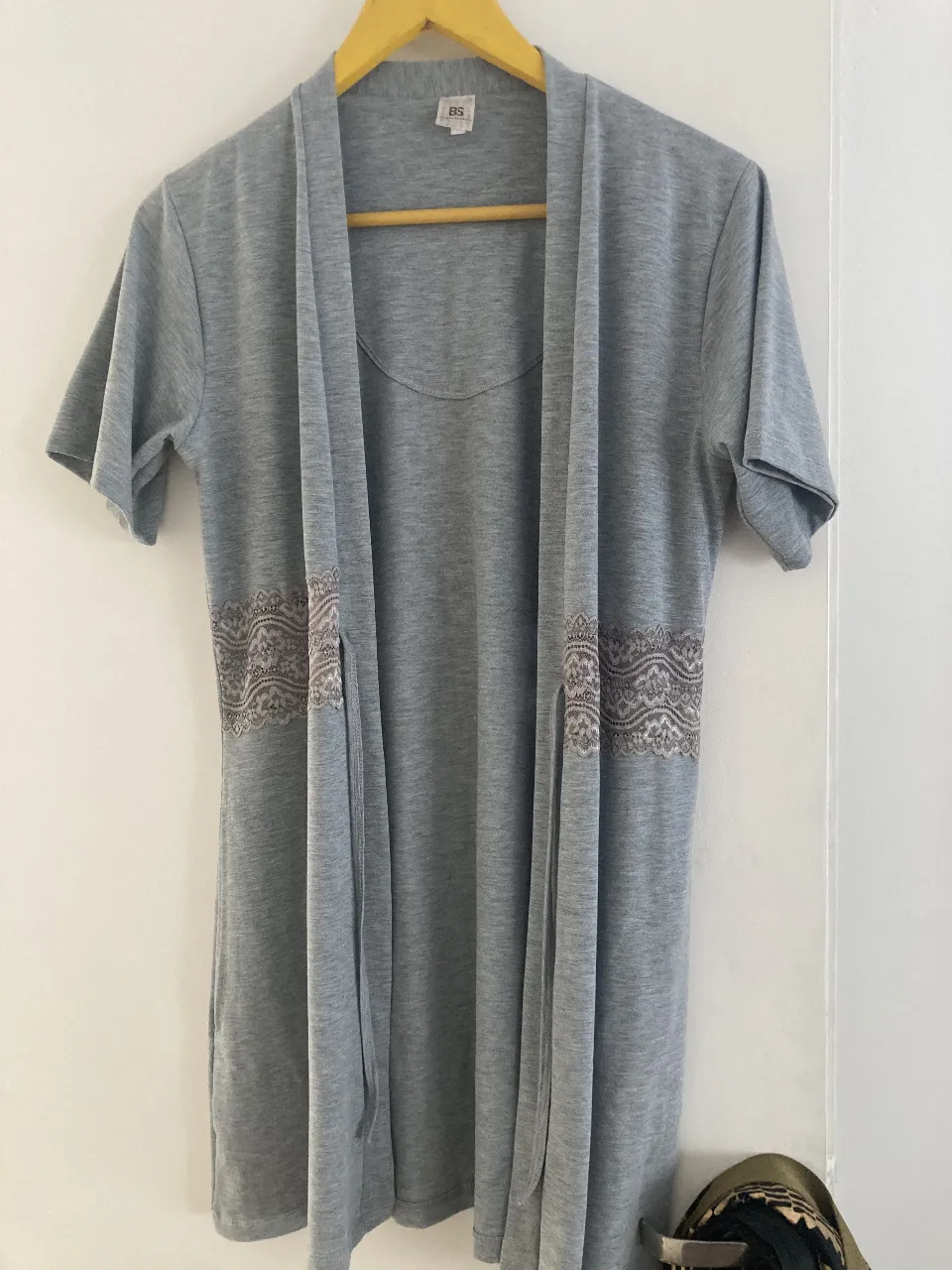 Bata gris con detalle de encaje en la cintura. Manga corta y diseño abierto. Ideal para un look casual y cómodo.