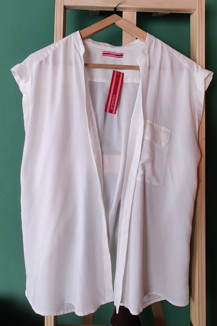 Camisa blanca sin mangas, con cuello mao y botones al frente. Posee un bolsillo en el pecho y un corte holgado. Ideal para un look fresco y moderno.