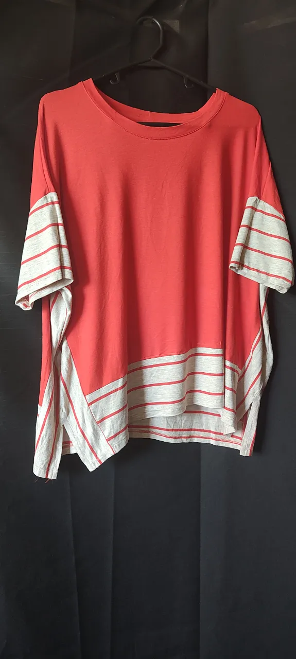 Remera de algodón color coral con detalles a rayas en mangas y ruedo. Diseño moderno y cómodo, ideal para el día a día.