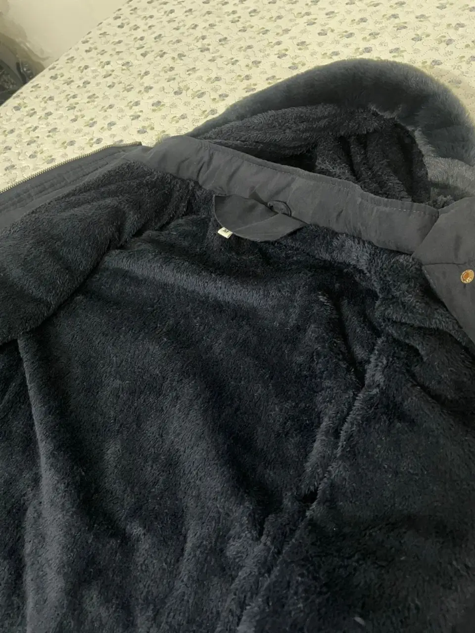 Campera de abrigo negra con capucha y forro de piel sintética. Posee cierre y bolsillos delanteros. Ideal para el invierno.