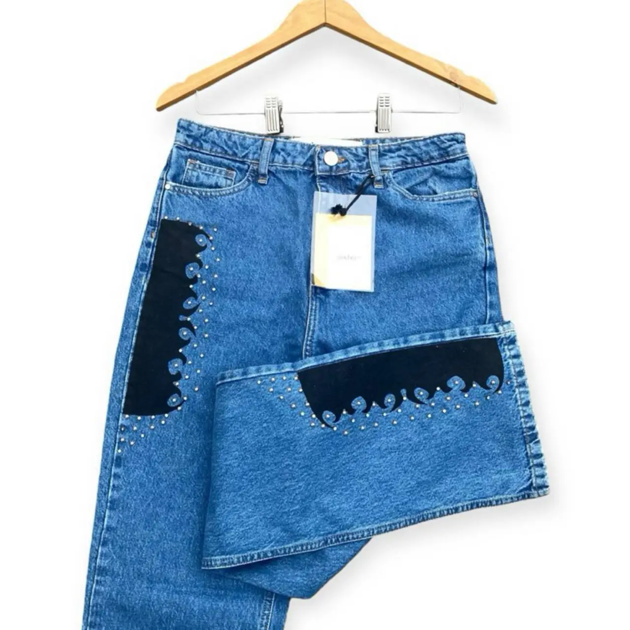 Jeans de mujer, tiro alto, con detalles de apliques en negro y strass en los laterales. Corte recto, ideal para un look casual y moderno.