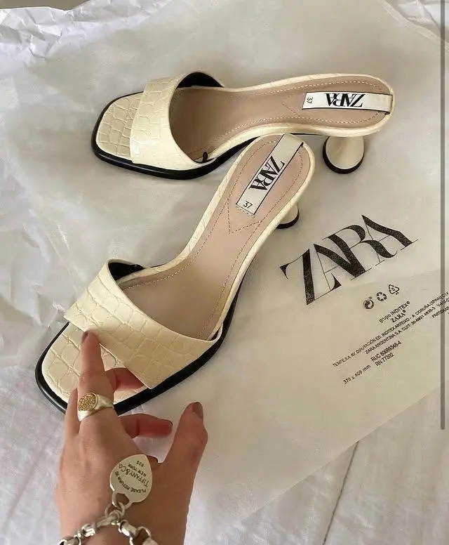 Sandalias de mujer Zara, color crema con detalles en negro. Diseño elegante con taco bajo y forma cuadrada. Ideales para un look casual o de fiesta.