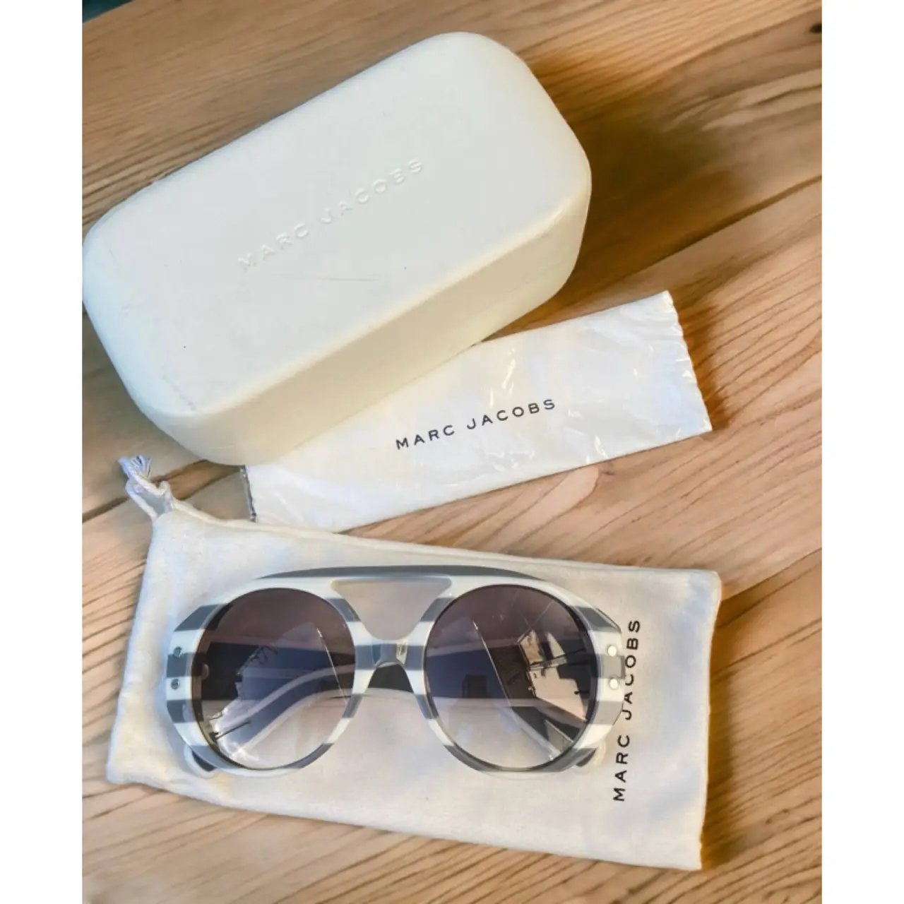 Anteojos de sol Marc Jacobs con diseño a rayas blanco y gris. Incluye estuche, funda y paño de limpieza.