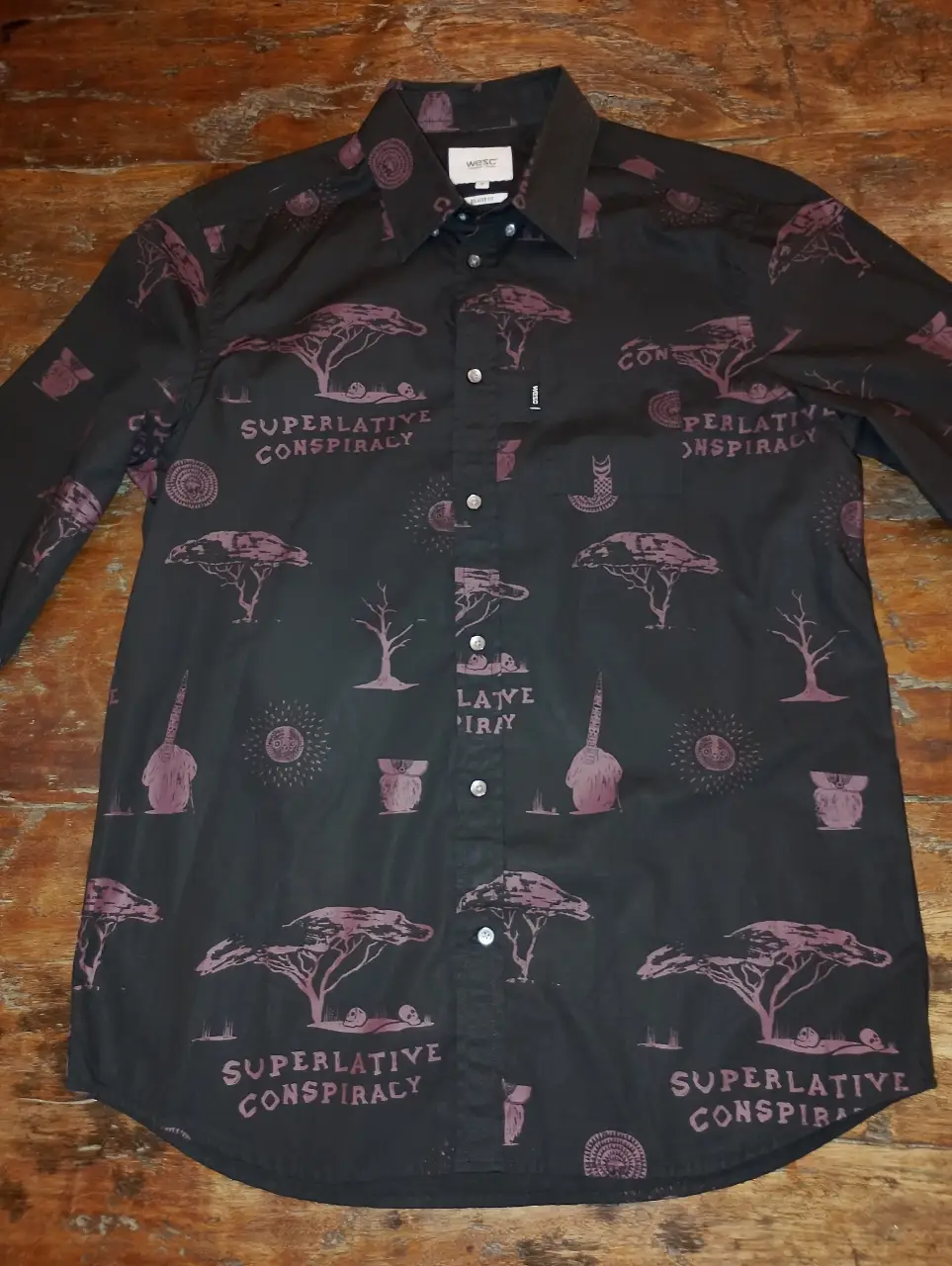 Camisa estampada de manga larga para hombre, con diseño "Superlative Conspiracy" en color burdeos sobre fondo negro. Ideal para un look casual y con estilo. Nueva sin estrenar.
