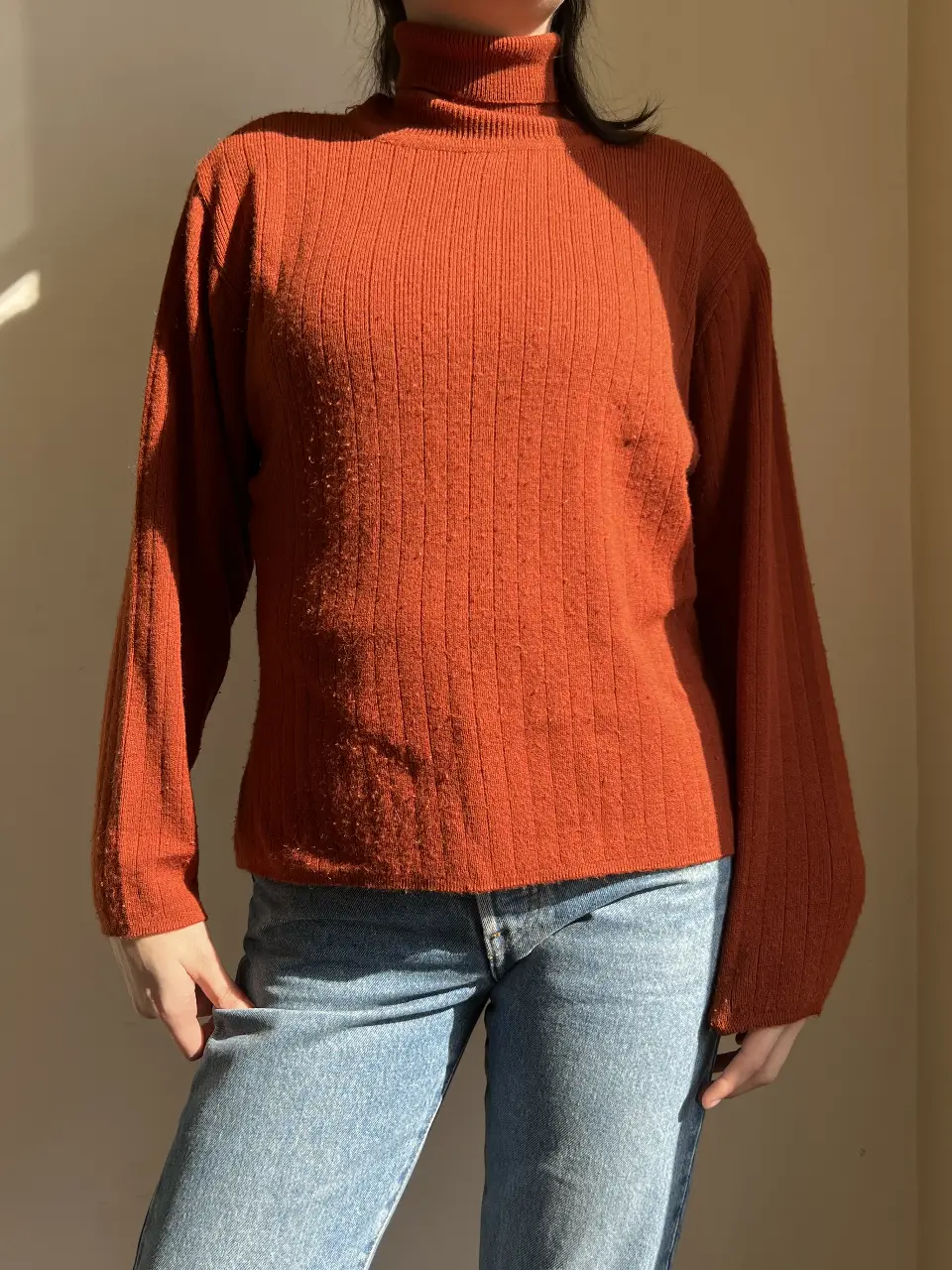 Sweater de cuello alto color naranja, tejido con textura acanalada. Ideal para un look casual y abrigado.