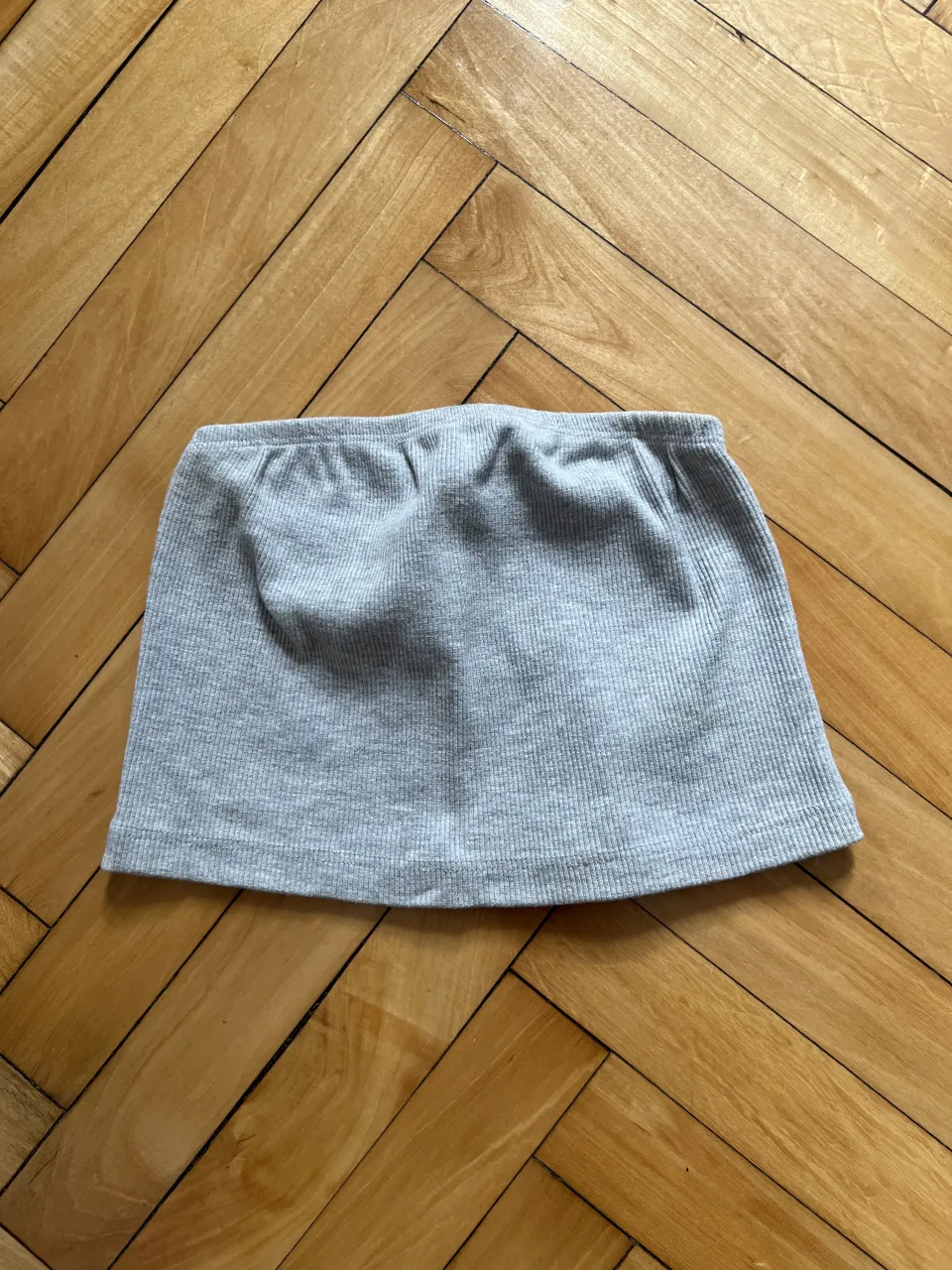 Top bando de tejido de canalé gris, sin mangas y sin tirantes.