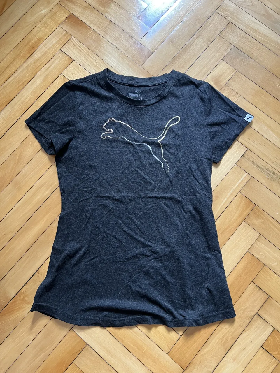 Remera gris con estampa del logo de Puma en dorado.