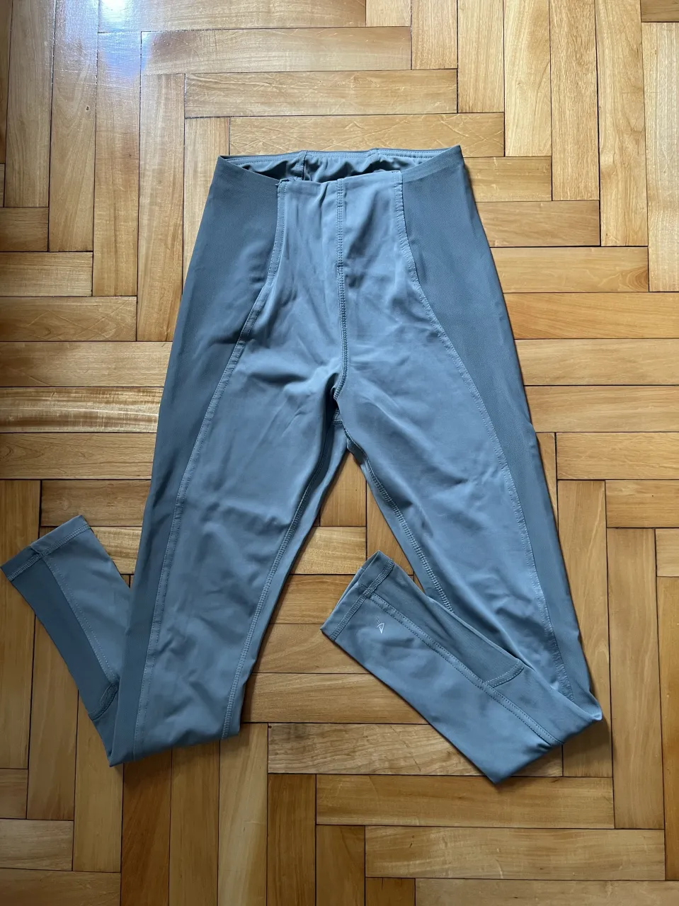 Calza deportiva gris con detalles de costura en los laterales y en las piernas. Posee cintura elastizada.