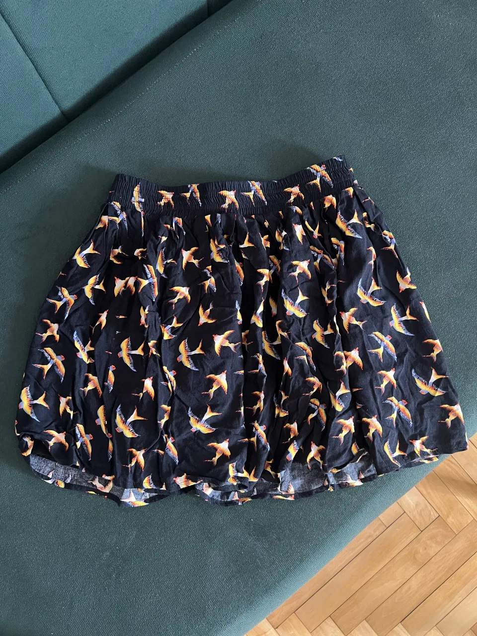 Pollera negra con estampa de pájaros en tonos naranja y amarillo.